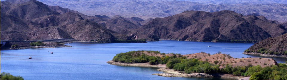 Photograph of an Arizona desert scene with a lake surrounded by low, rounded hills; mountains in the background; used with permission of the photographer