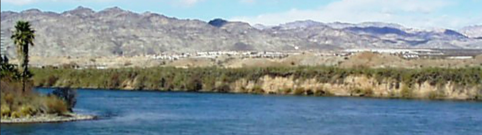 Photograph of an Arizona desert scene with water in the foreground; buildings in the mid-ground; mountains in the background; used with permission of the photographer